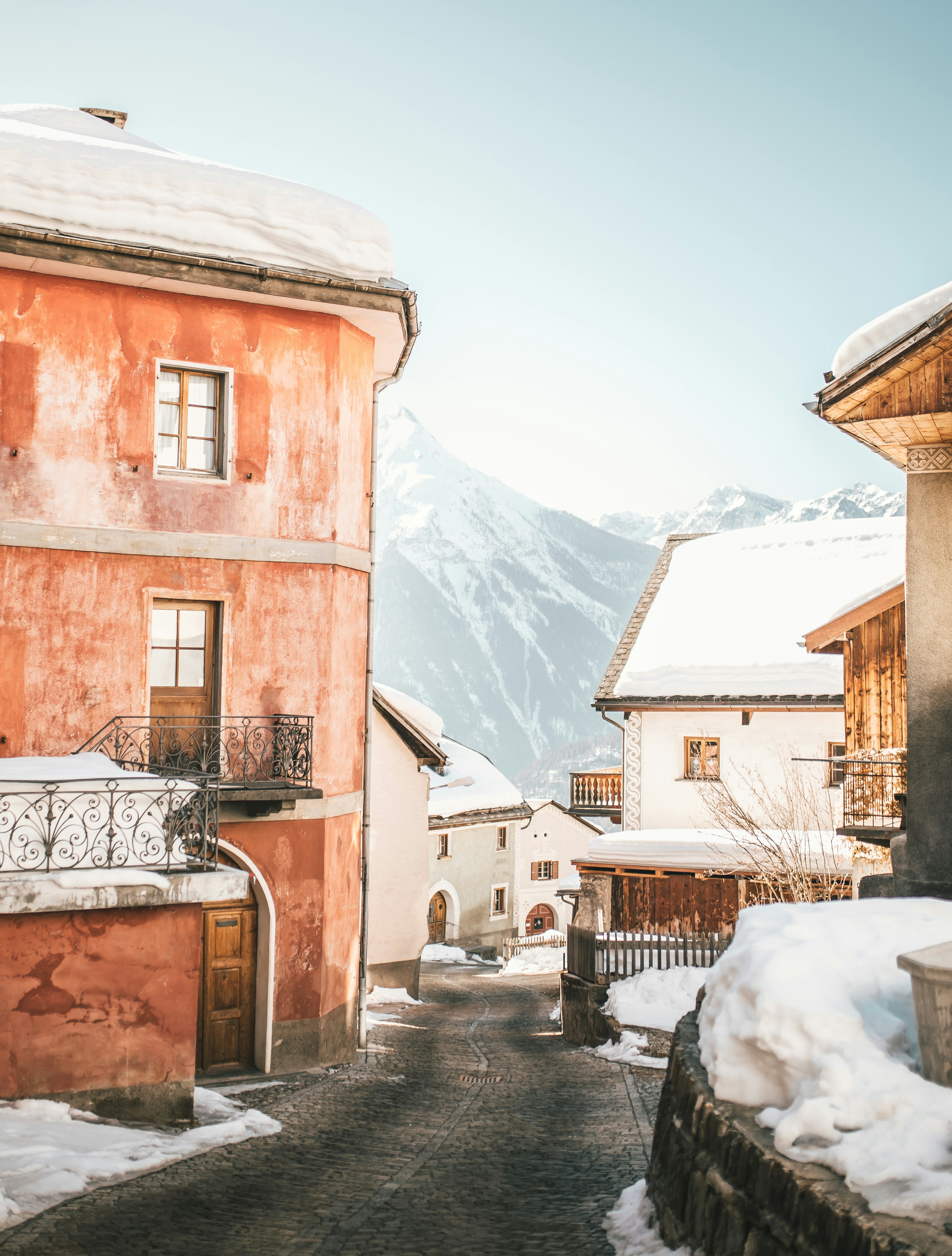 brown concrete building near snow covered mountain during daytime